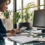 Close-up of hands manually calculating payroll in healthcare office
